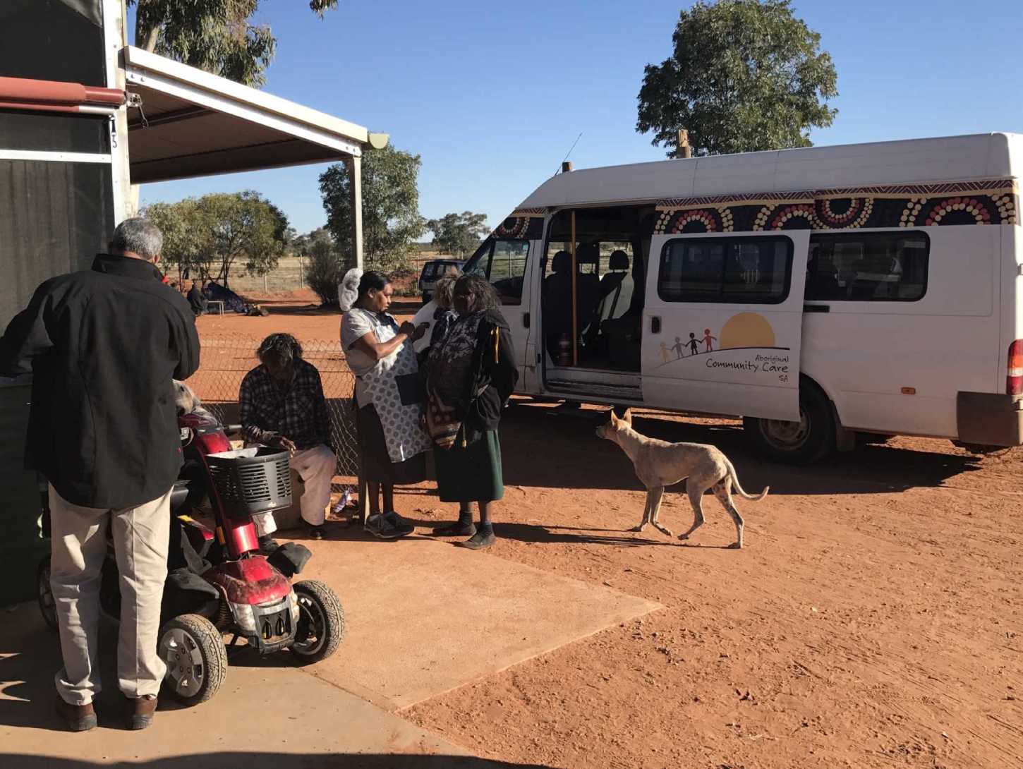 Aboriginal Elders standing next to a residence in APY Lands area and receiving supplies from the ACS van transport