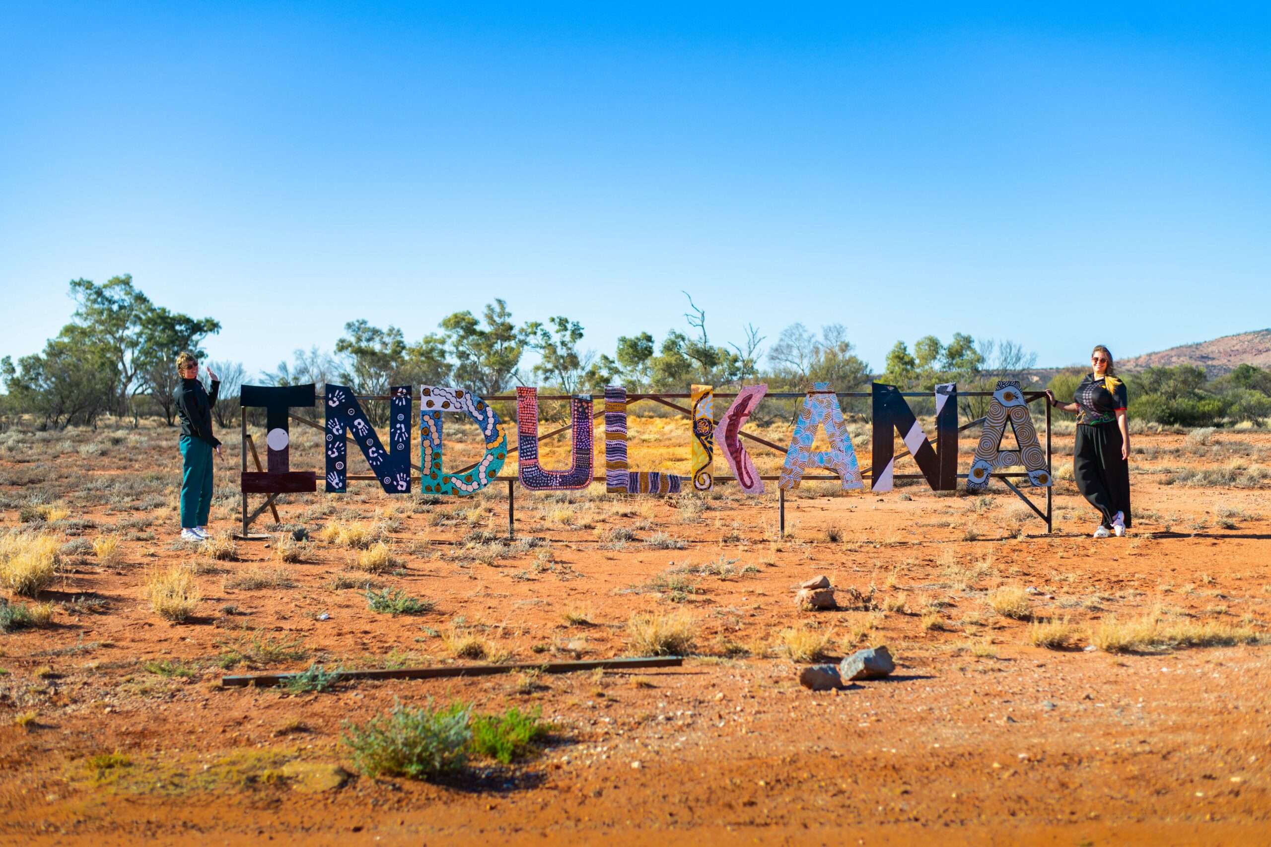 Aboriginal Community Services staff in next to Indulkana sign in the APY Lands.
